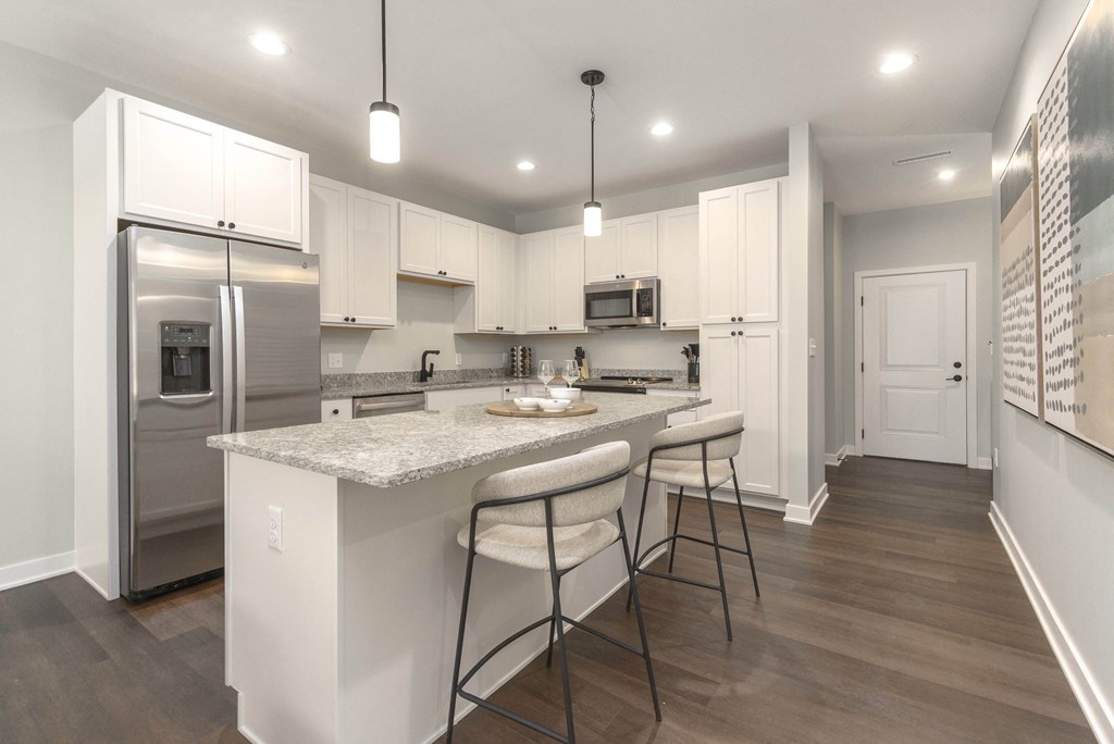 a kitchen with white cabinets and a marble counter top